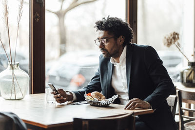 Businessman using smart phone while having lunch in restaurant