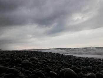Scenic view of beach against cloudy sky