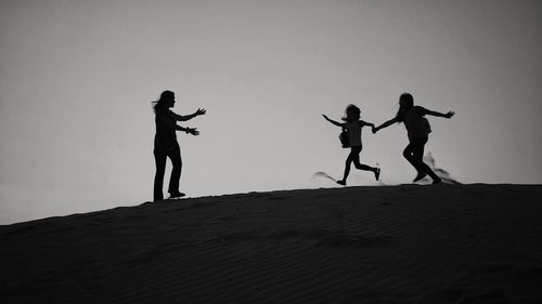 Silhouette people standing on land against clear sky