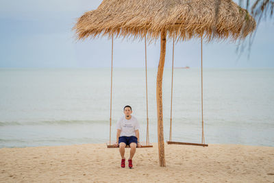 Full length of boy standing on beach against sky