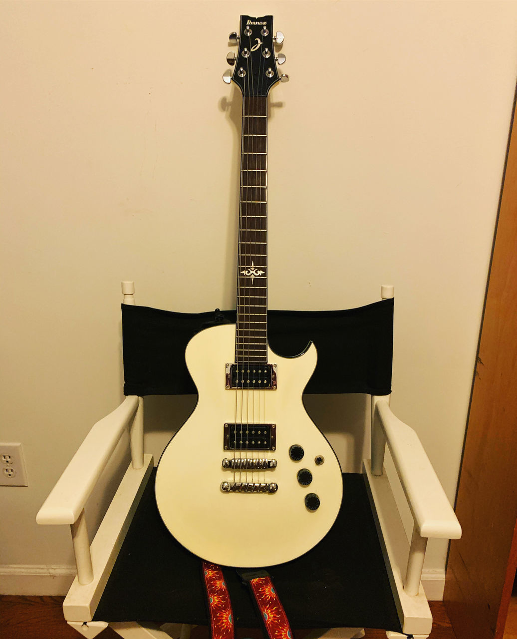 CLOSE-UP OF GUITAR ON CHAIR AGAINST WALL