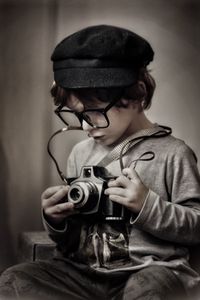 Cute boy holding camera sitting outdoors