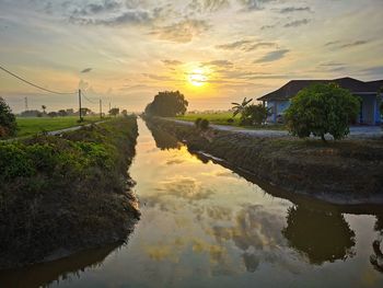 Scenic view of canal against sky during sunset