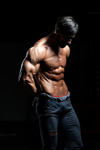 Rear view of man standing against black background