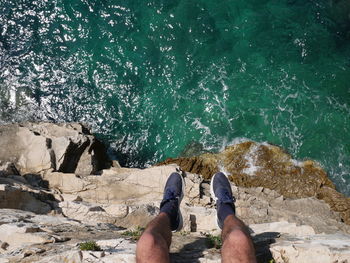 Low section of man on rock by sea