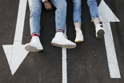 Unrecognizable young couple sitting between the signs on the floor of a skate park