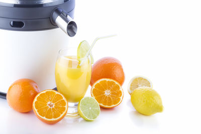 Close-up of citrus fruits with juicer on white background