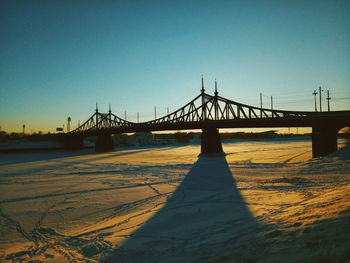 Suspension bridge over river against clear sky