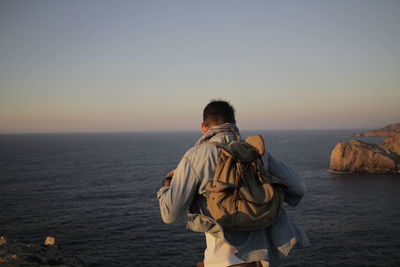 Rear view of man standing in sea against clear sky