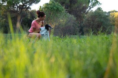 Side view of woman with dog on grassy field