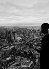 Man looking at cityscape against cloudy sky