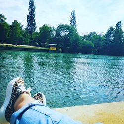 Low section of person by lake against trees