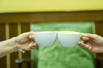 Cropped hand holding coffee cup against blurred background