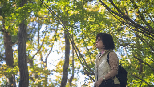 Side view of woman standing against trees