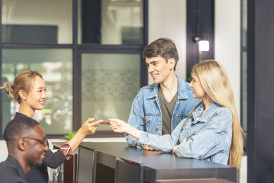 Guests handing their check-in information to the hotel receptionist with a smile