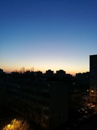 Silhouette cityscape against clear sky during sunset