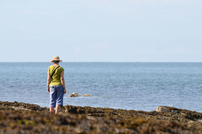 Rear view of woman standing in sea against sky