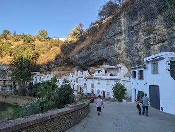 Rear view of people walking on street amidst buildings in city