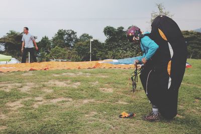 Side view of man with parachute standing on grass