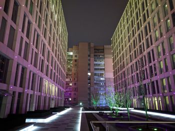 Illuminated street amidst buildings in city at night