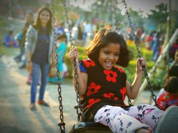 Smiling girl sitting on swing at playground