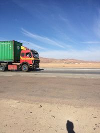 Vintage car on desert land against blue sky