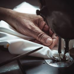 Cropped hand of woman using sewing machine