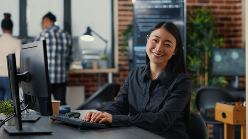 Portrait of young woman using laptop at office