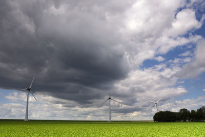 Wind turbines on field against sky
