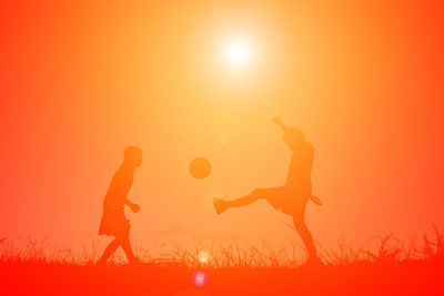 Silhouette of men jumping at sunset