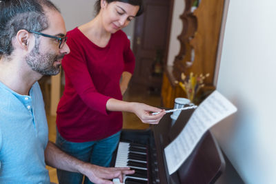 Woman teaching man to play piano at home