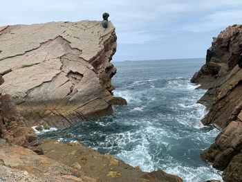 Rock formation on sea shore against sky