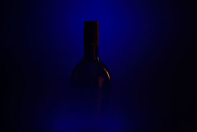 Glass of bottle against blue background