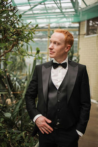 Portrait of young man groom standing against plants
