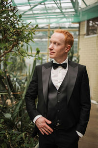 Portrait of young man standing against plants