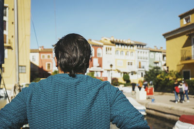 Rear view of man standing in city against sky