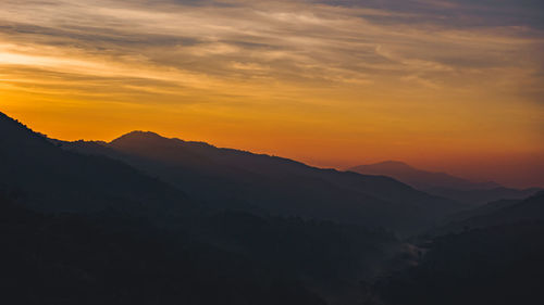 Scenic view of silhouette mountains against orange sky