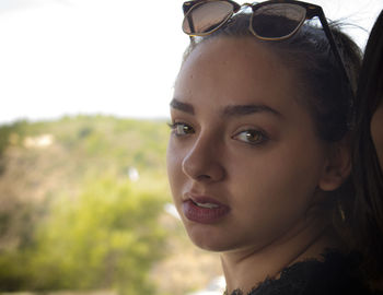 Close-up portrait of young woman against sky