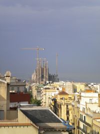 Buildings in city and sagrada familia against sky