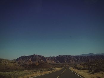 Road by mountains against clear blue sky