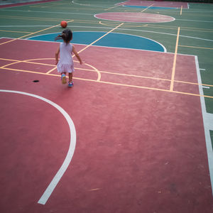 Full length of girl playing with basketball