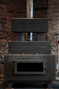 Close-up of old metal on table against brick wall