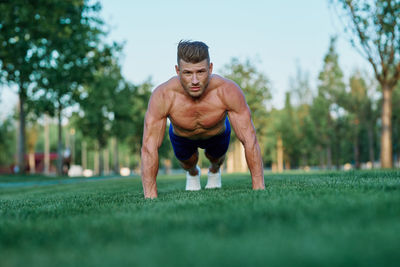 Portrait of young man exercising on field