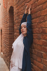 Low angle view of woman standing against brick wall