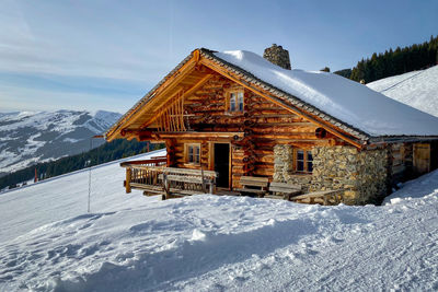 House on snow covered mountain against sky