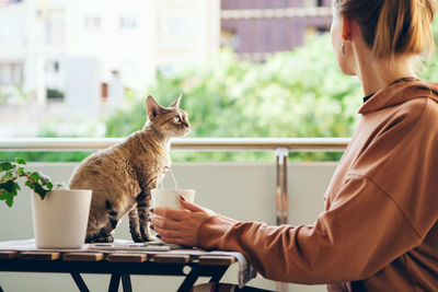 Side view of woman with cat on table