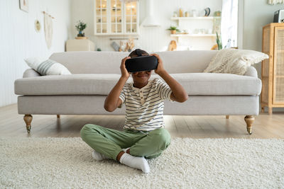 Side view of woman sitting on sofa at home