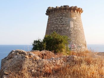 Stone wall by sea against clear sky