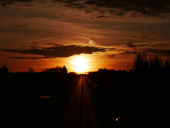 Silhouette railroad tracks against sky during sunset