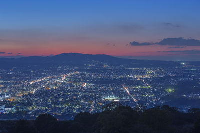 High angle view of illuminated cityscape against sky at sunset